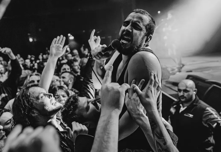 Adelaide rock band Bad//Dreems frontman performing passionately into a microphone while leaning directly into a crowded audience at a live gig.